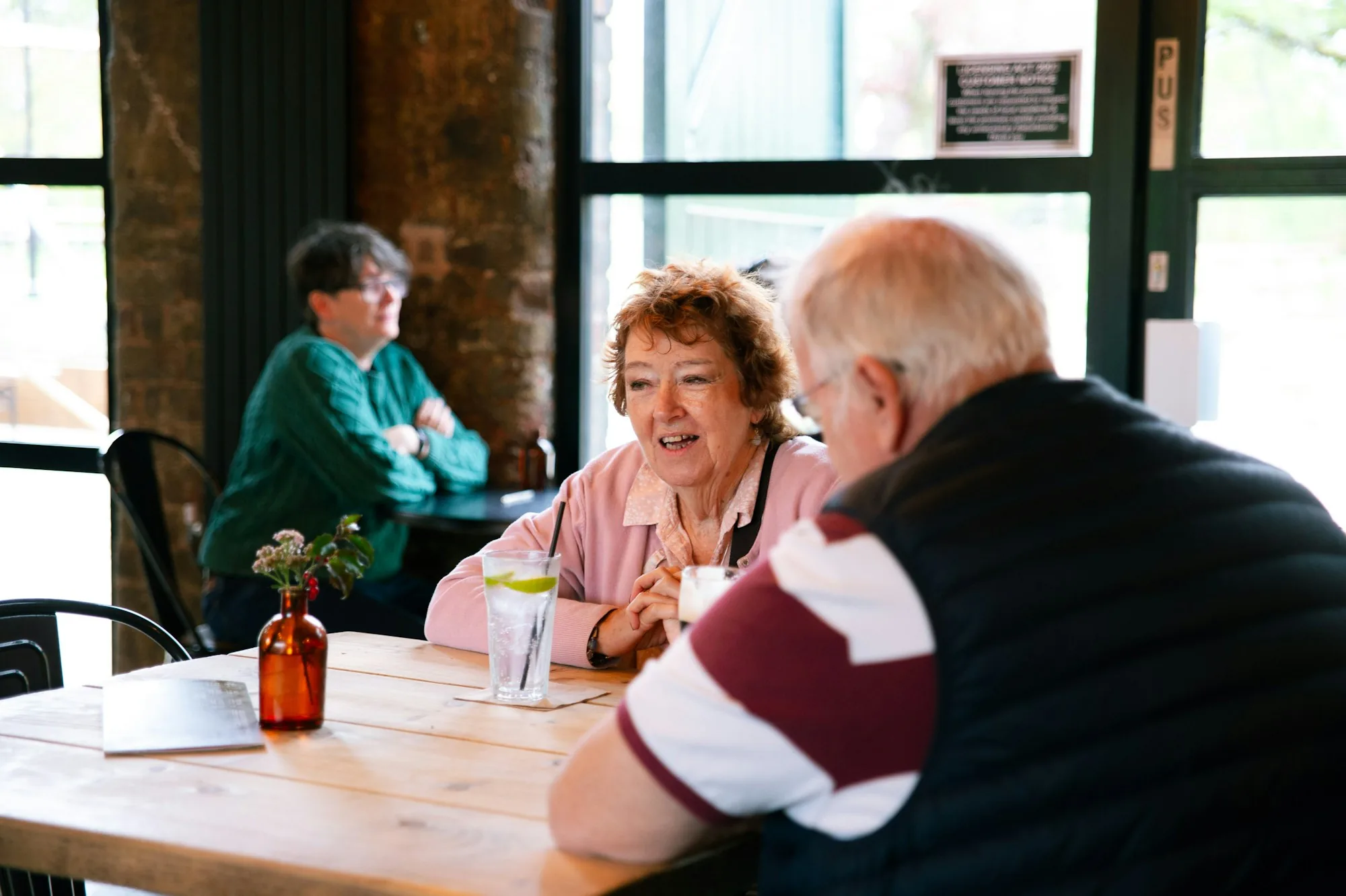 Two couples laughing together over coffee at a cafe table